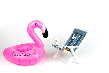 Sun lounger and inflatable Flamingo isolated on white background. Tropical vacation background. Sun lounger on the sandy island, copy space, front view