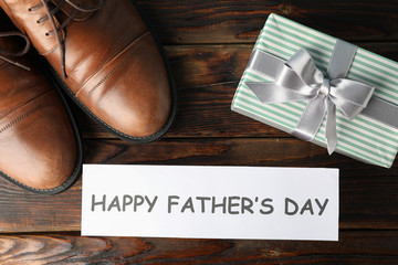 Brown leather shoes, inscription happy fathers day and gift box on wooden background, space for...