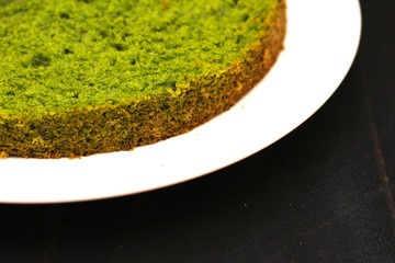 green round spinach mint cake on a white plate on a black background
