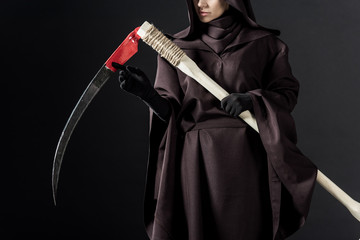 cropped view of woman in death costume holding scythe on black