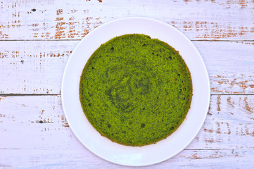 green round spinach mint cake on a white plate on the table with shabby boards