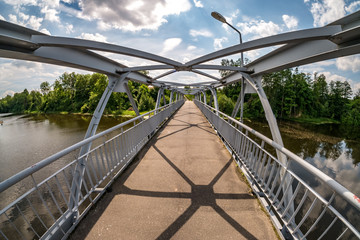 Obraz premium iron steel frame construction of pedestrian bridge across the river. wide angle view