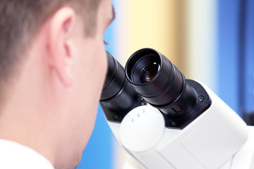 man looking through a microscope closeup. research in pharmacology and science.