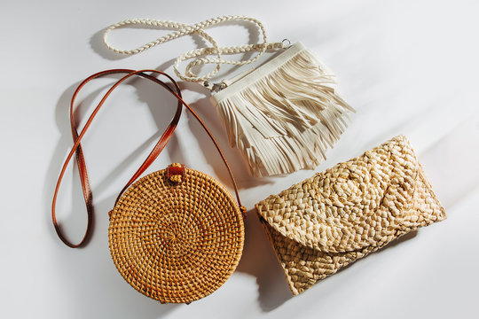 Variety summer handbags on white background. Round bamboo bag, handbag with fringe and straw bag. Flat lay, top view. Fashion concept.