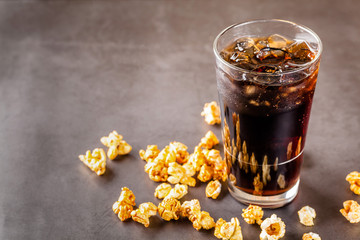The concept of food for the cinema, for watching a movie. Cold cola drink with ice in a glass...