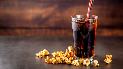 The concept of food for the cinema, for watching a movie. Cold cola drink with ice in a glass...