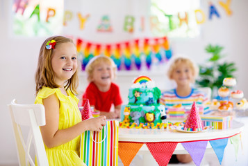 Fototapeta premium Child birthday party. Kids blow candle on cake.