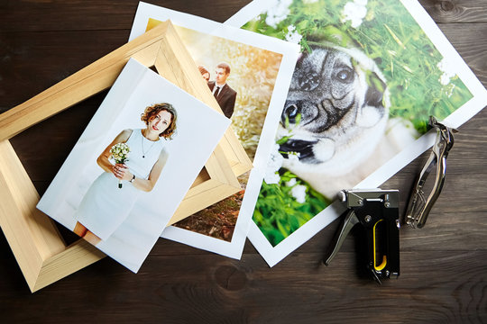 Photo canvas prints. Tools for wrapping.  Photographs, stretcher bars, staple gun and canvas pliers.  Printed photos of a dog and a wedding couple lying on a wooden table. Top view