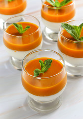 panna cotta with mango puree in a glass on a marble surface