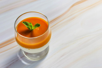 panna cotta with mango puree in a glass on a marble surface