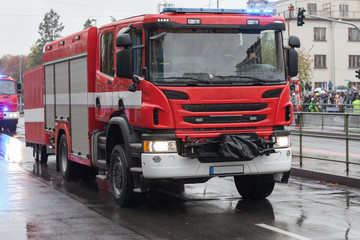 Fototapeta na wymiar Fire brigade workers are riding fire truck on military parade