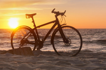 Fototapeta na wymiar Bike and sunset by the sea. Black bike by the sea.