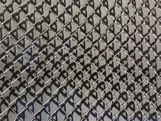 Horizontal sectional close up view of a chainlink fence with dark canvas  behind