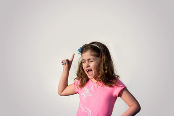 Little girl screaming and pointing her finger against gray background