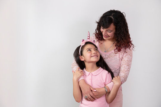 beautiful mom with curly hair hugging her little daughter from behind tenderly and lovingly