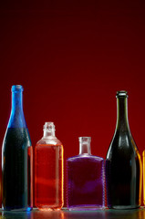 Different alcoholic drinks in transparent bottles on red background