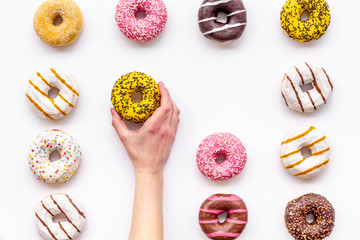 Donuts of different flavors for breakfast in hand on white background top view