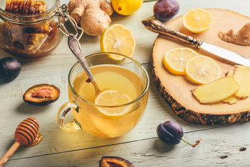 Cup of tea with lemon, honey and ginger over wooden surface