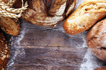 Different kinds of bread and bread rolls on board from above. Kitchen or bakery