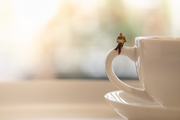 Reading, relaxing, hobby concept. Close up of businessman miniature mini people figures sitting  on...