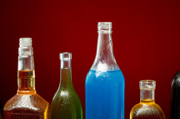 Different alcoholic drinks in transparent bottles on red background