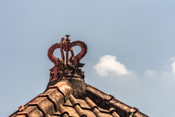 Dusun Ambengan, Bali, Indonesia - February 25, 2019: Clan compound. Closeup of red crown-like decoration on top of red tile roof of one of the memorials for ancestors.