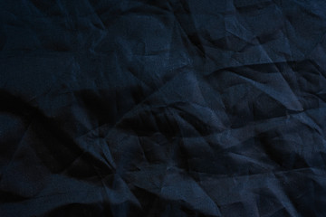 Macro of the texture of a wrinkled plastic fabric of black color, background for designs.
