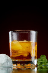 Glass with alcohol in a transparent glass with ice and mint on a red background