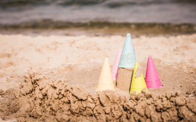 bunte Sandspielzeug Eisbecher aus Plastik an einem Strand getürmt zu einer Burg