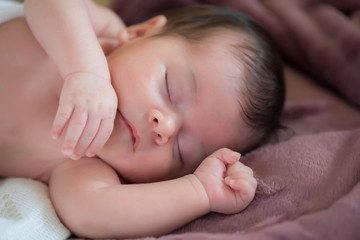 closeup of beautiful newborn baby asleep on a violet blanket