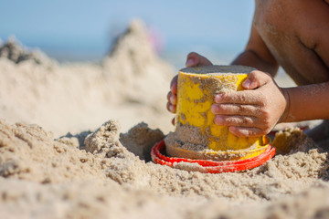 Kind spielt mit Eimer im Sand am Strand