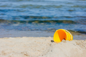 gelber Kinder-Eimer am Strand 