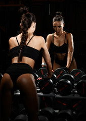 Fototapeta na wymiar Sporty young woman working out with dumbbells weight in Gym. Diet and weight loss concept