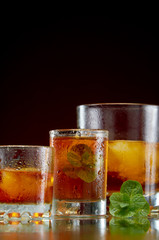 Alcoholic drink in glasses with ice and mint on red background