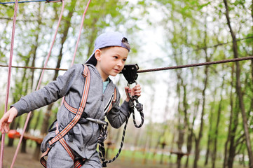 a small child preschooler boy is an obstacle in a safety alpinism equipment high rope Park
