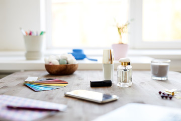 Color palette, smartphone and some self-love items such as bottle of scent, candle, lipstick and nail enamel on wooden table