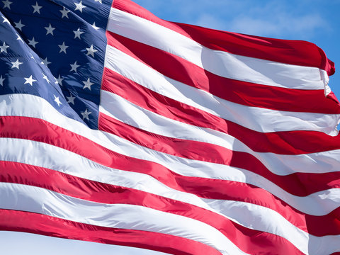 Extreme Close Up of an American Flag with Blue Sky and Thin Clouds in Background