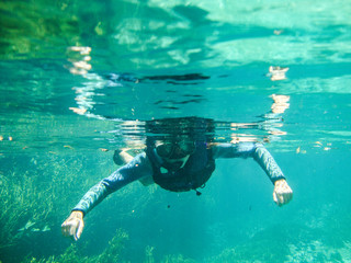 Girl snorkeling at Sucuri river water surface, crystal clear, transparent blue river, in Bonito, Mato Grosso do Sul, Brazil