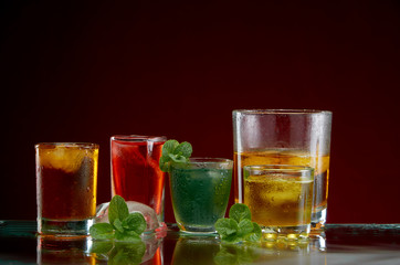 Set of alcoholic cocktails with ice and mint on a red background