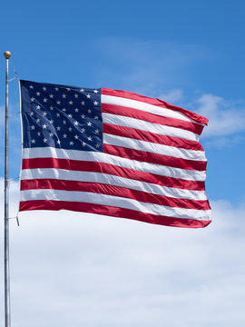 Vertical American Flag on Flag Pole with Blue Sky and Thick White Clouds