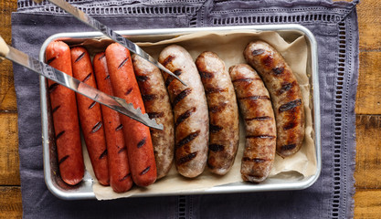 tray of grilled hot dogs and bratwursts on tray in top down composition