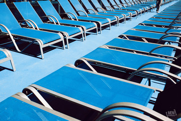 Blue lounge chairs on wooden floor on a Mediterranean sea cruise.