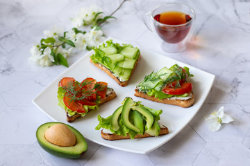 Vegetarian sandwiches with avocado, tomatoes and cucumbers on a light background