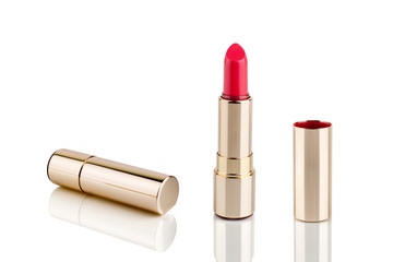 Red lipstick in golden tube on white background with mirror reflection on glass surface isolated...