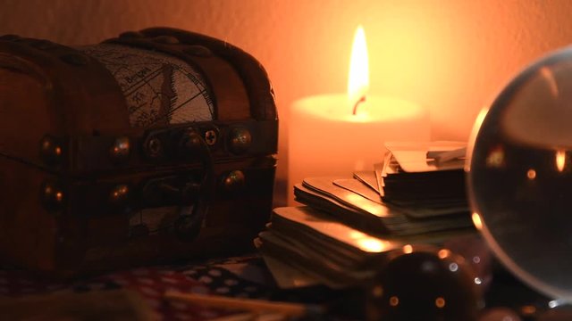 Background of a fortune teller table covered with fabric, with crystal balls, stones, matches, cards and candles with flickering flames