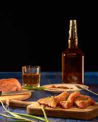 Fresh meat with spices on wooden Board and alcohol standing on blue table and black background