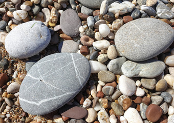Multicolored large pebbles of various shapes on the sandy shore of the Mediterranean sea for backgrounds