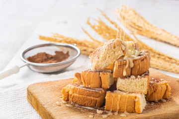 sweetened condensed milk pouring down into pile of bread on wooden cutting board