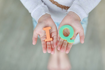 IQ (Intelligence Quotient) sponge text on child hands. Education and development concept. - obrazy, fototapety, plakaty