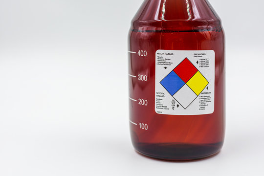 laboratory amber glass bottle with blank health hazard label on a field of white used in biology and medical research..